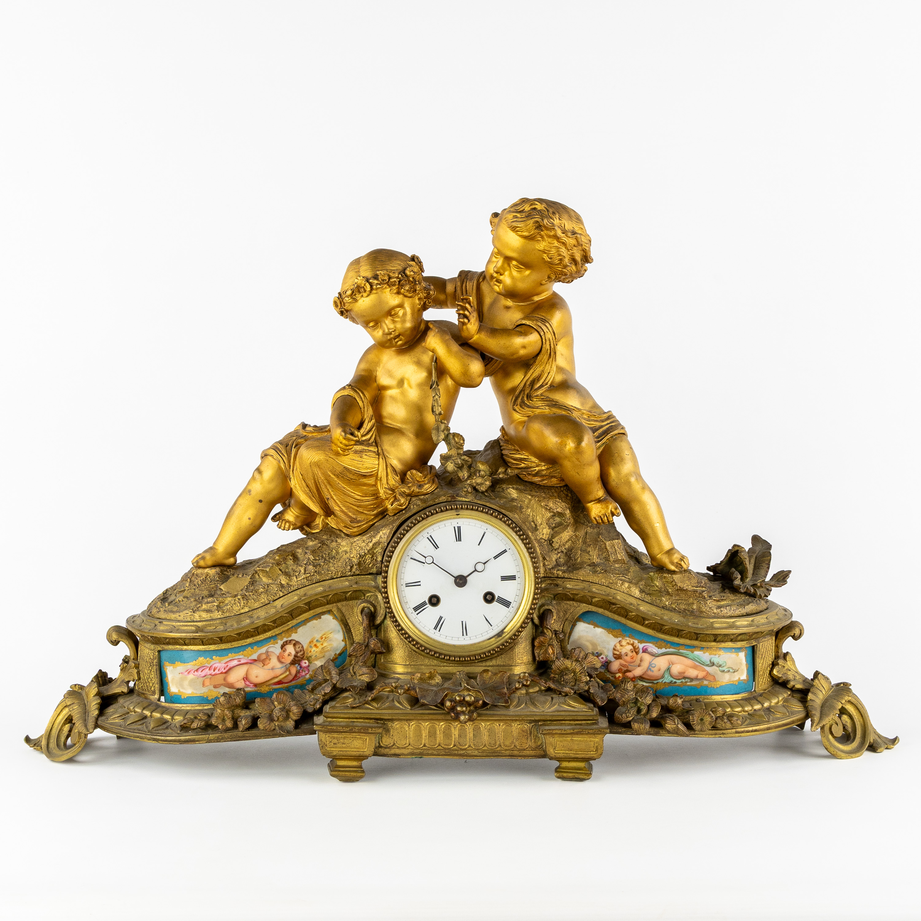 Een pendule met twee putti en porseleinen plaquettes in Sèvres stijl, verguld brons, Frankrijk, Napoleon III, 19de eeuw. (L:70 x W:18 x H:44 cm)